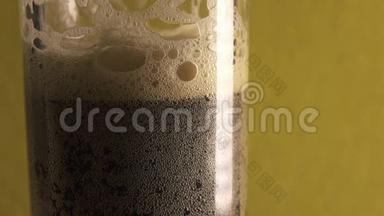 棕色泡沫饮料克瓦斯或啤酒倒在玻璃杯里，一小瓶泡沫破裂，手拿走一个玻璃杯